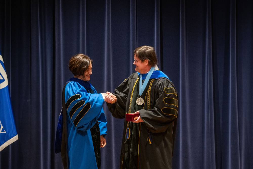 Provost Mili shaking hands with faculty member